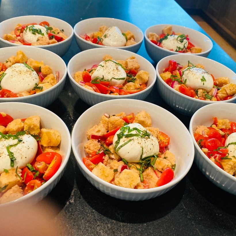 Individual bowls of tomato and bread salad topped with burrata