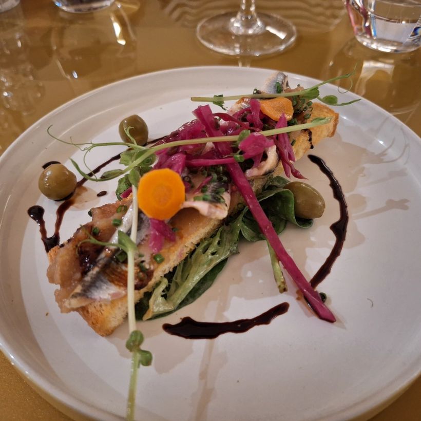 A composed plate of fish with pickled vegetables and herbs